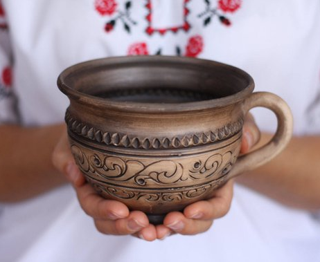 A person holding a handmade mug.