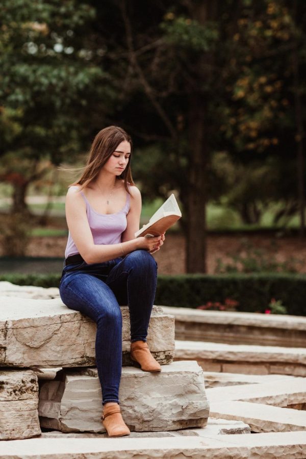 A senior, Kiley Brockway, sits while reading a book