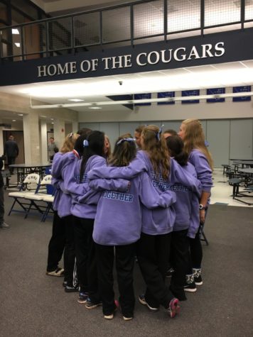 This image shows the girls team standing together in a circle with arms around each other. 