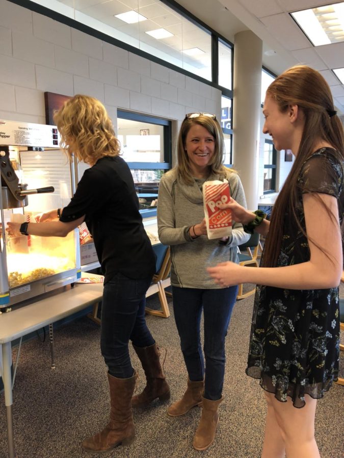 Caitlin Fagel (11) receives popcorn from Ms. Curry and Ms. Bellito on a special day where popcorn was served at Camp Khan in the IRC.