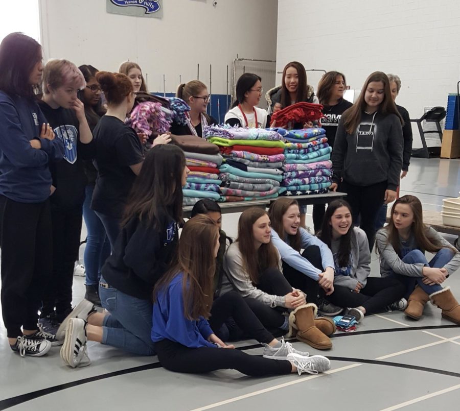Students pose in front of a stack of blankets