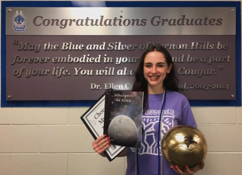 Cassidy Dipinto smiles, posing in front of the graduate sign.