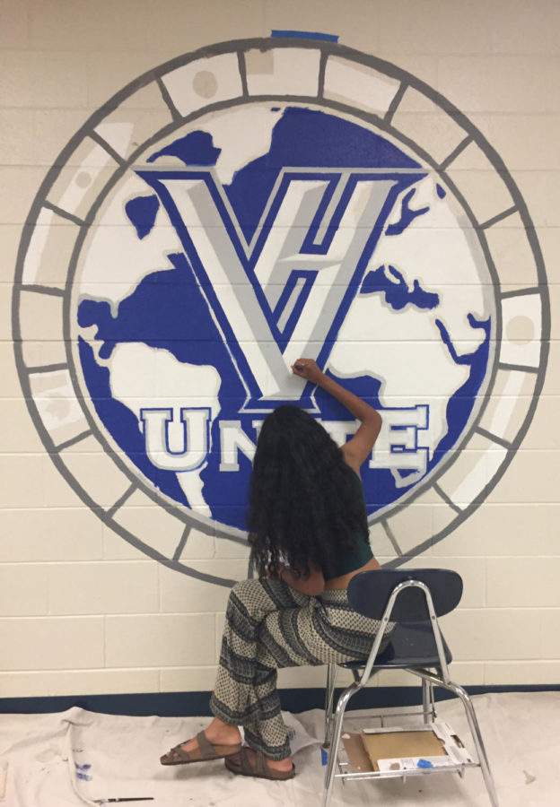 This photo shows a student painting a mural of a globe.