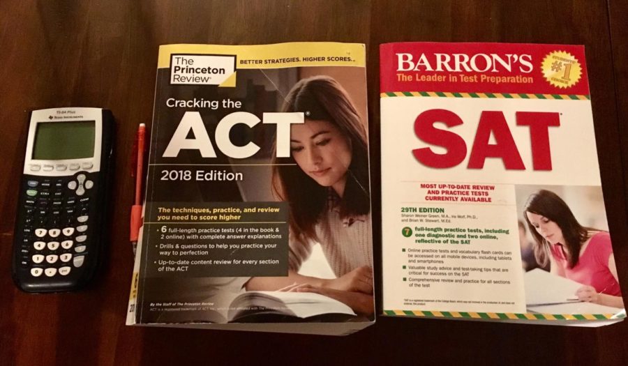 Picture of an SAT practice book next to an ACT practice book with a calculator.