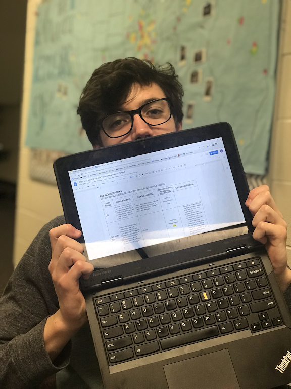 Noah Proft (12) is holding his computer in front of his face. The computer appears to be in good condition.