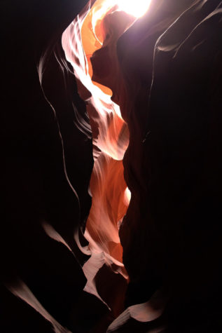 A photo of a light shining through a rocky backdrop.