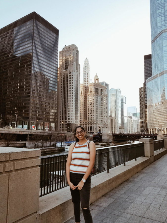 Sanjana is standing on the bridge in front of some skyscrapers