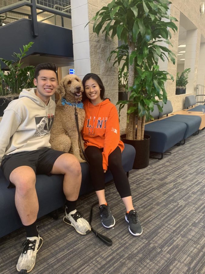 Students Justina Chua (right) and Alex Tantasook (Left) sit next to Basil the dog