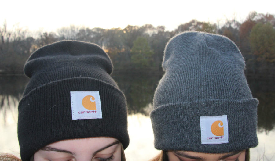 A close up shot of two girls wearing Carhartt beanies. The one on the left is a black beanie and the one on the right is a grey beanie.