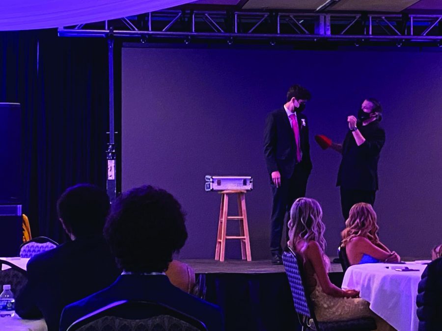 A student and magician stand on stage together.