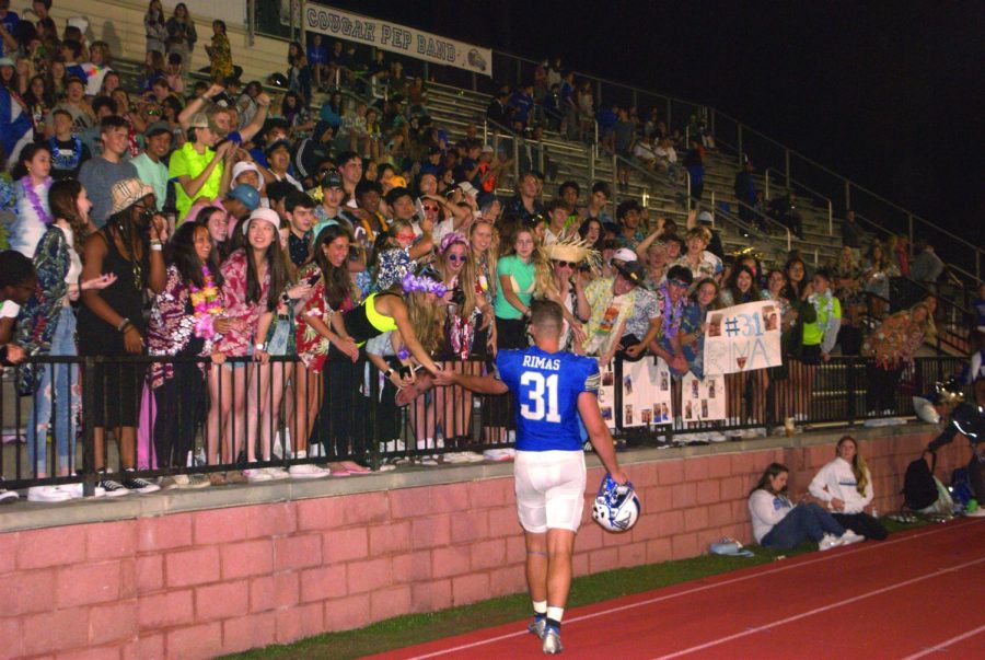 A football player approaches the stands and gives fans high fives.