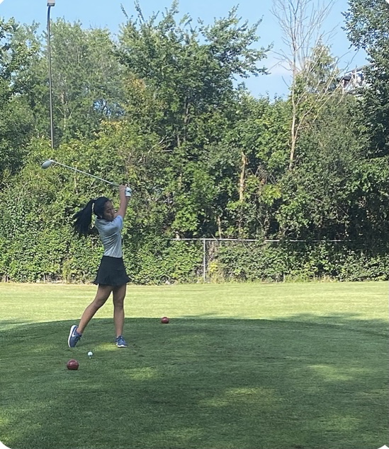 A member of the girls golf team takes a swing.
