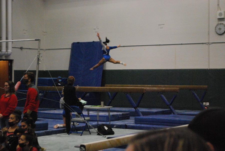 Ally Dominguez (10) leaps into the air during routine on balance beam.
