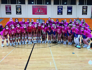VHHS volleyball team huddles up for a picture to show off their pink jerseys for breast cancer awareness.