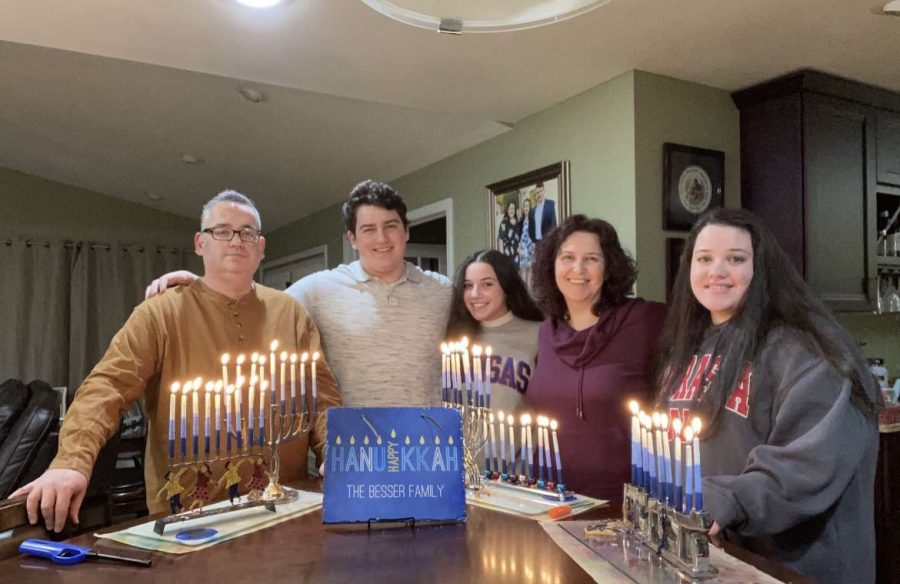 Sarah Besser (11) and her family pose in front of their five lit menorahs on the eighth night of Hanukkah 2021