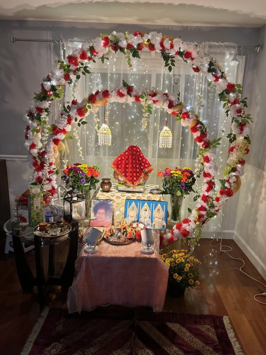 A hindu alter with many lights, flowers, photos, with a ganesha pictured in the middle.