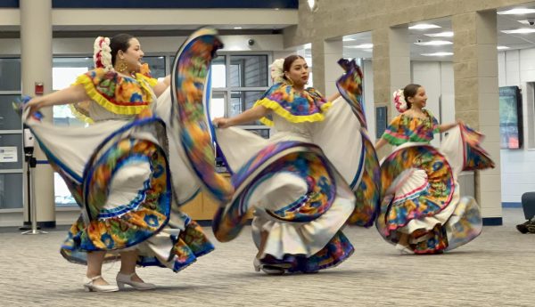 Three folkloric dance performers twirl their dresses. 