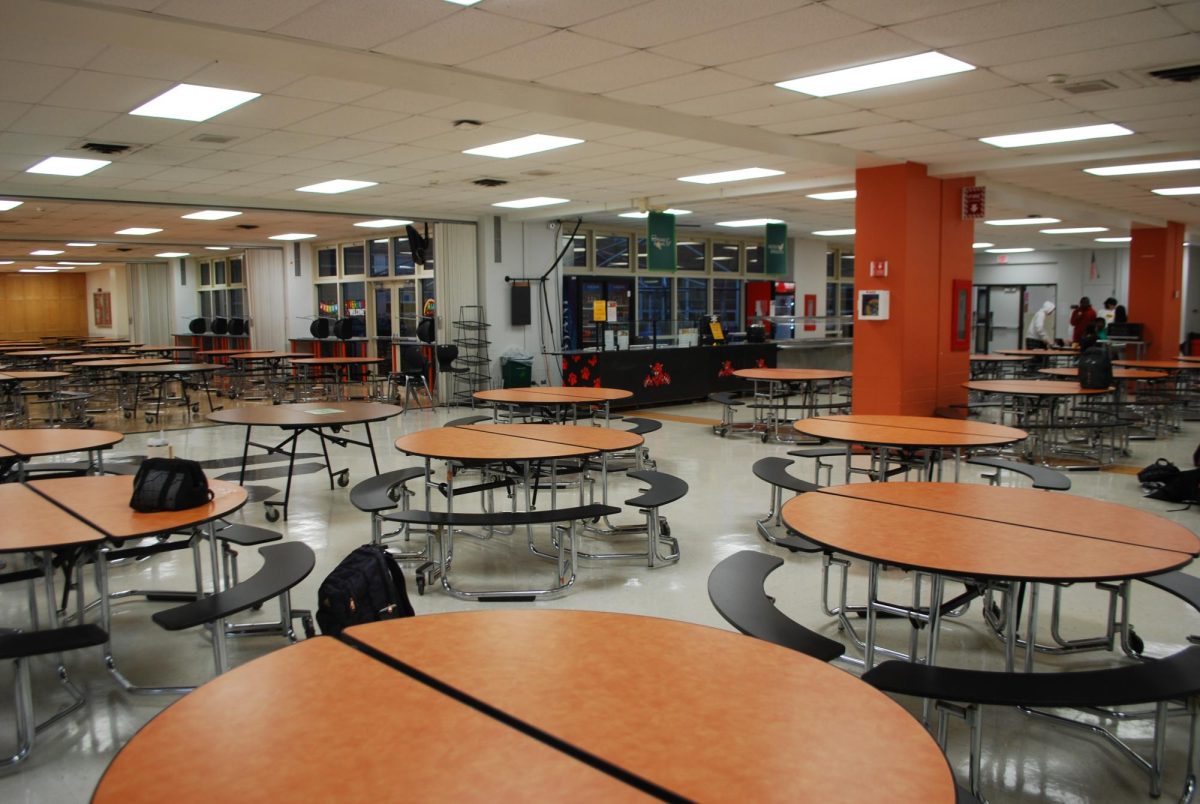 Tan+cafeteria+tables+surrounding+L-shaped+room+with+orange+pillars.