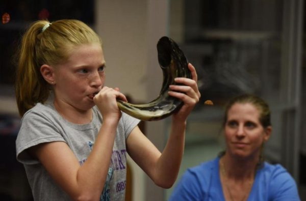 Young Romy Miller (12) blows the Shofar, a musical horn as a morning tradition for Rosh Hashanah.