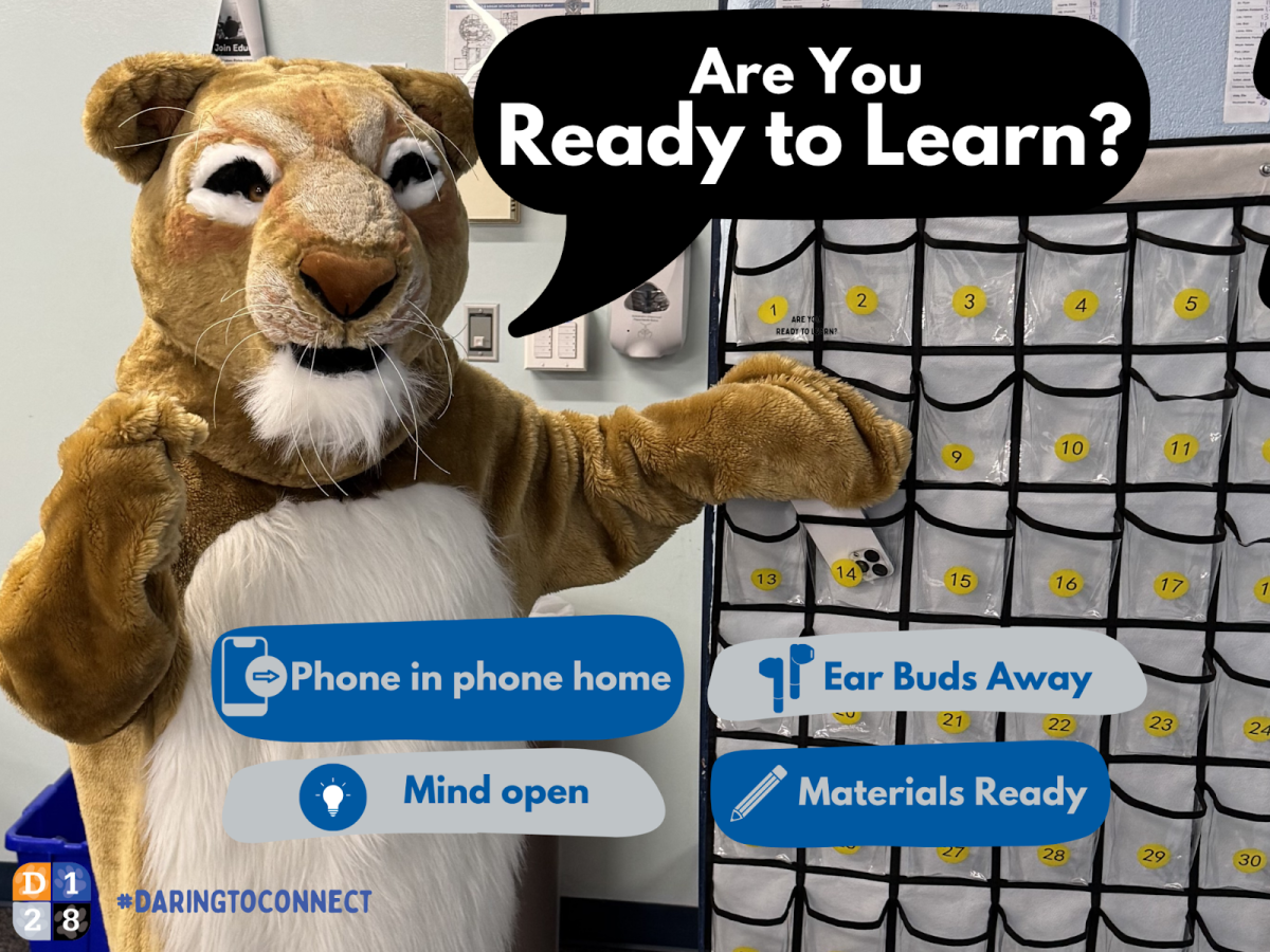 Cody the Cougar points to the Cell Hotel in a classroom.