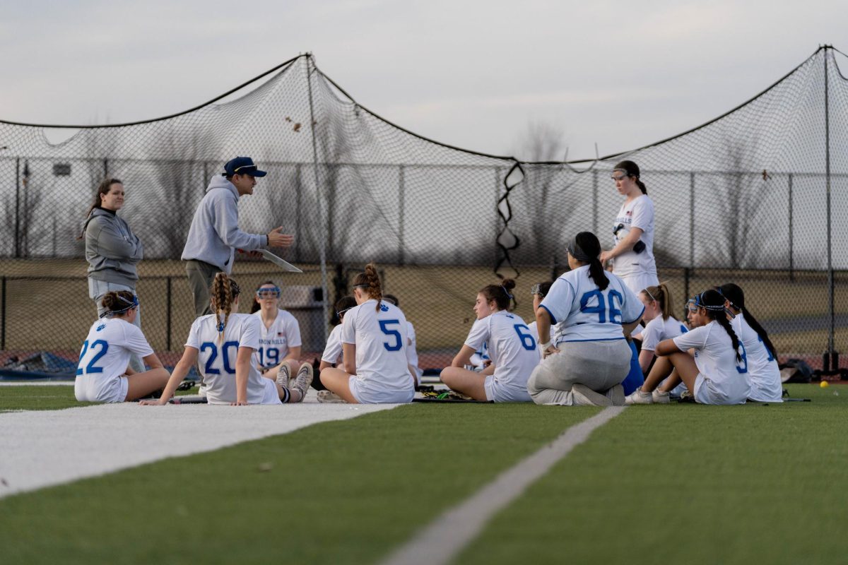 Vince Tran discusses strategy with the lacrosse team during a game.